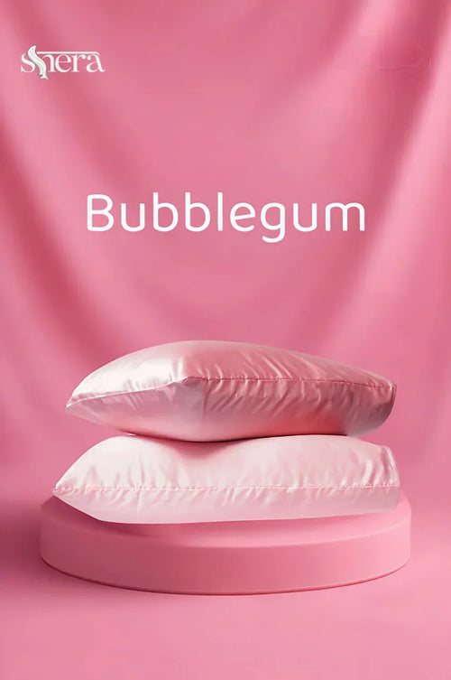 Two pink satin pillowcases on a round platform, bubblegum color, with pink background.