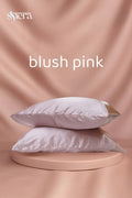 Two blush pink satin pillowcases stacked on a circular platform with a matching background